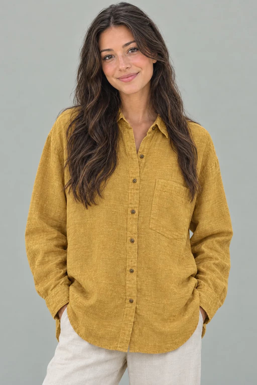 Model berpose tiga per empat mengenakan kemeja linen mustard di studio